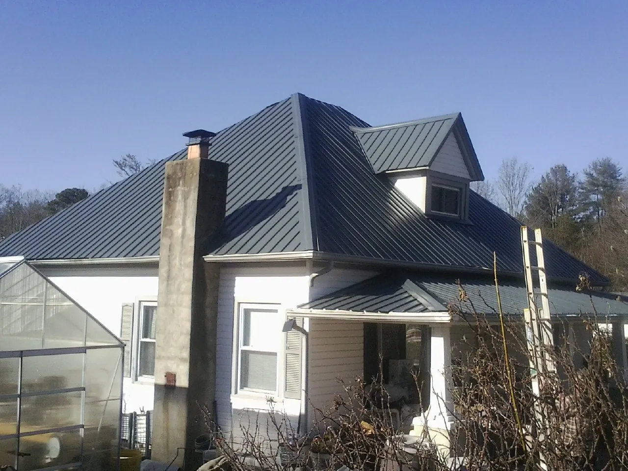 Dark blue standing seam metal roof on a white farmhouse with dormer — Slate & Tile Roof Repair by Roofing Brothers in Turtle Creek