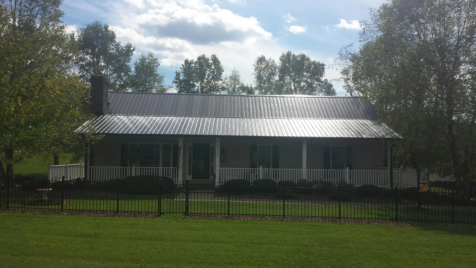 Gray metal roof on a brick ranch with a full width front porch — Gutter Guard Installation work by our crew in Turtle Creek