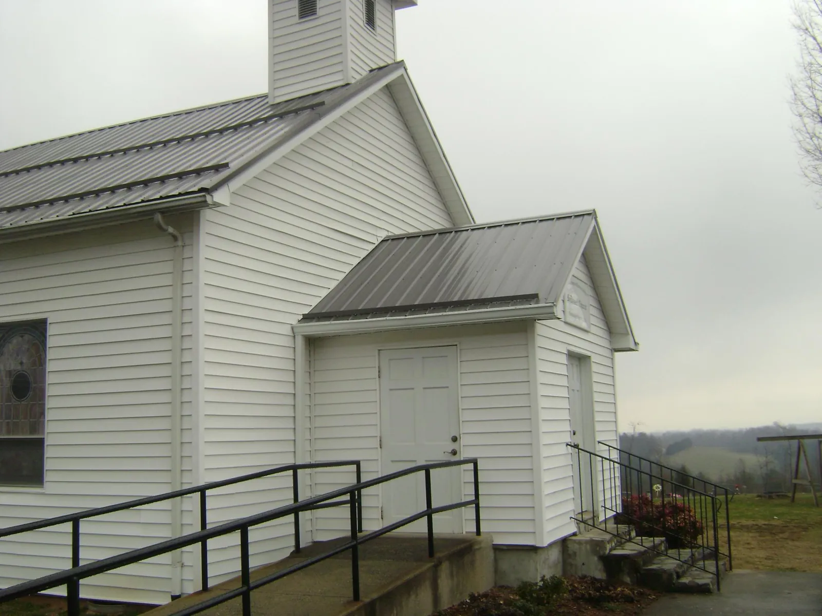 Gray metal roof on a white clapboard church with a steeple in Turtle Creek