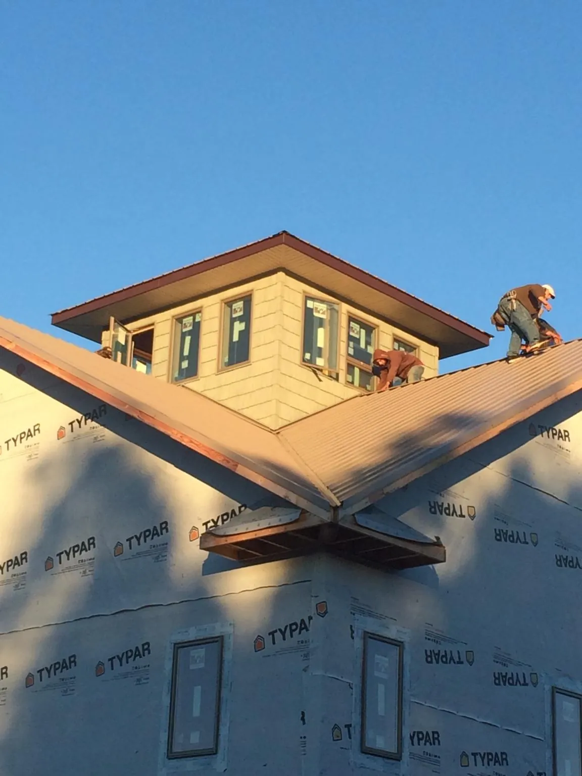Roofers working around a rooftop cupola on a new metal roof at sunset — Roof Waterproofing in Turtle Creek by Roofing Brothers